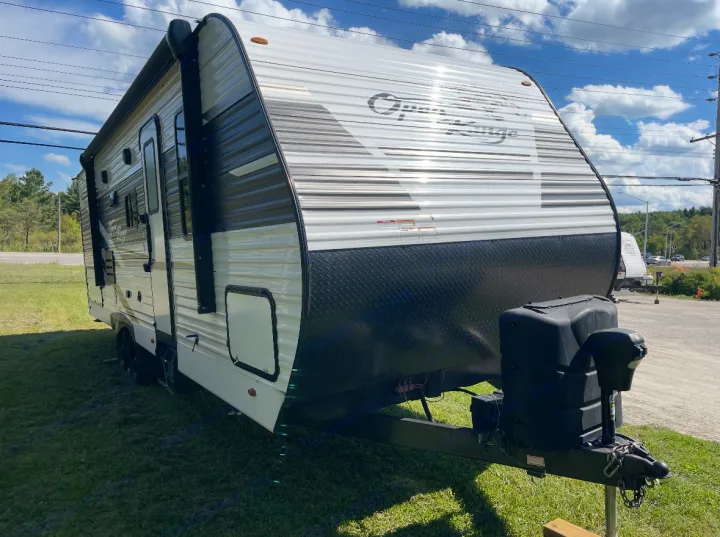 Front and side view of a white and black "Open Range" RV rental travel trailer, parked outdoors on grass.. Highland Ridge RV Open Range 2022