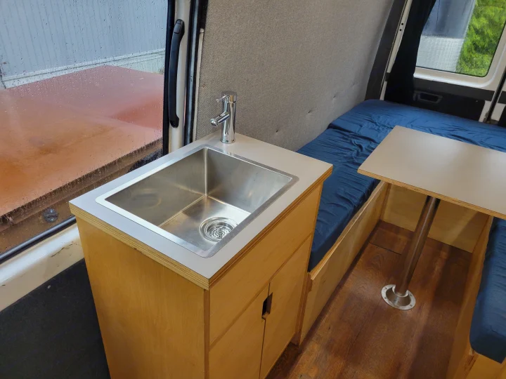 Inside this RV rental: compact kitchen sink, cozy bed, and versatile table. Perfect for mobile living.. Mercedes Sprinter 2006