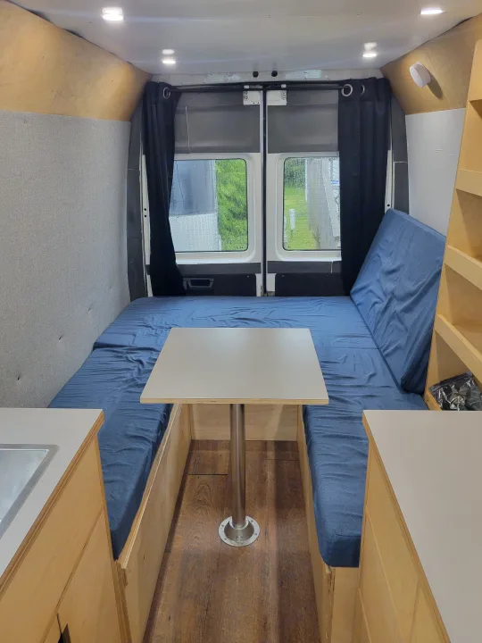 RV rental: Camper van interior with a convertible bed/dinette area, central table, and light wood-paneled walls.. Mercedes Sprinter 2006