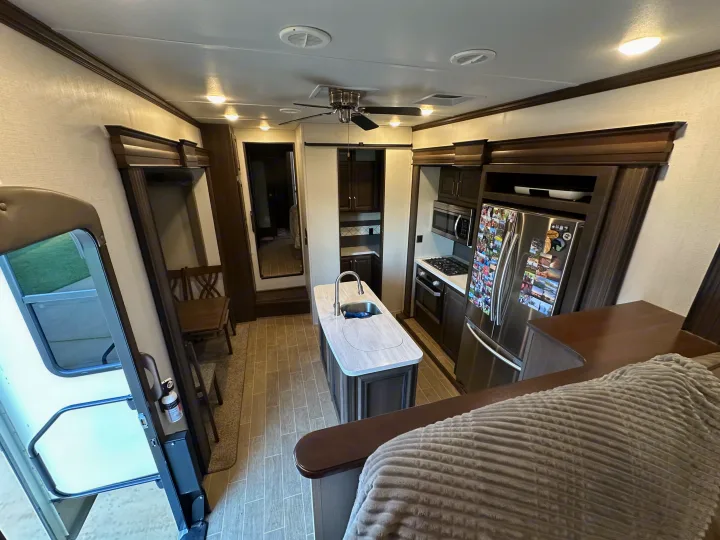 Spacious RV rental interior showing a modern kitchen with island, dining area, and partially seen living space in the foreground.. Keystone RV Alpine 2021