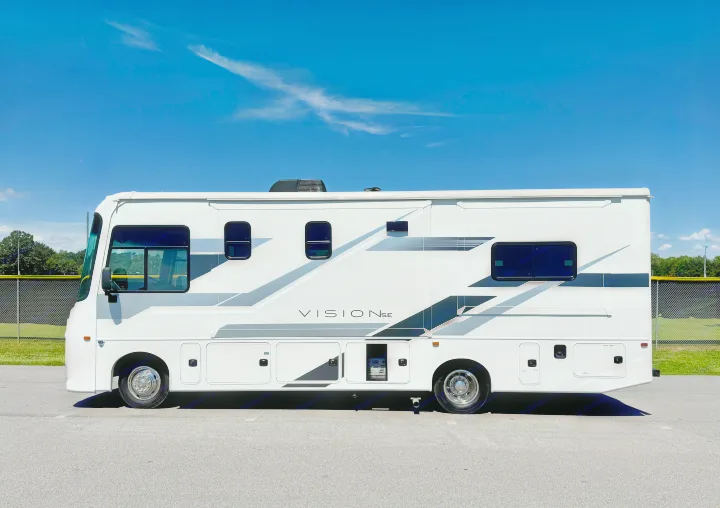 White RV rental (VISION SE) parked outdoors, featuring sleek grey/black graphics against a bright blue sky & park.. Entegra Coach Vison 27ASE 2025