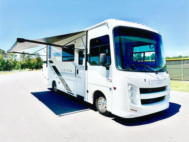 White Entegra Coach Vision SE RV rental with awning extended, parked on asphalt under a clear sky.. Entegra Coach Vison 27ASE 2025