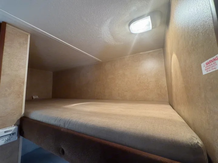 Inside an RV rental, this cozy bunk bed features a mattress, overhead light, and a 300lb capacity warning.. Jayco Jay Flight Swift SLX 2012