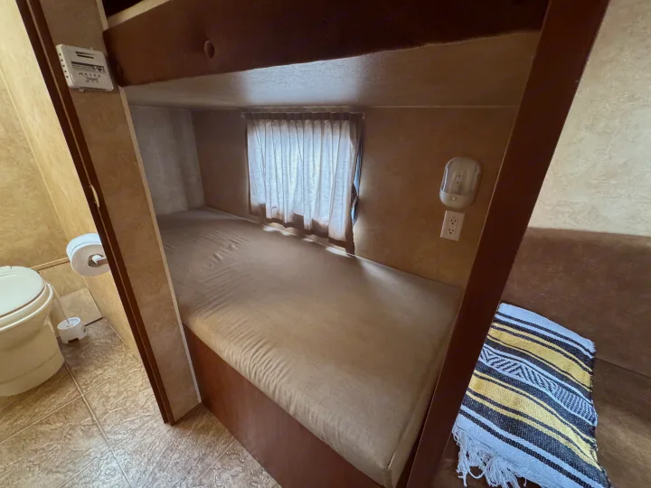 Cozy RV rental interior featuring a compact bunk bed, functional bathroom, and efficient amenities.. Jayco Jay Flight Swift SLX 2012