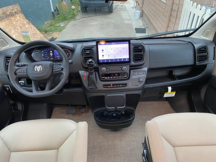 Modern RV rental cockpit with a large infotainment screen, digital dashboard, steering wheel, and comfortable front seats.. Thor Rize 2023