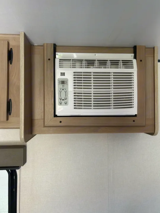 This RV rental cabin features a built-in air conditioning unit with digital controls, integrated into light wood cabinetry.. Coleman Lantern 17B 2025