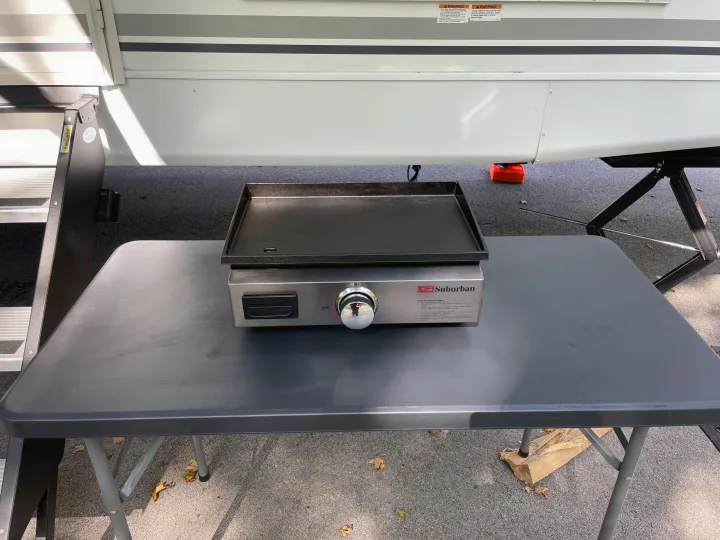 Portable griddle on a table next to an RV. Ideal for rv rental outdoor cooking adventures.. Coachmen Freedom Express Ultra Lite 2025