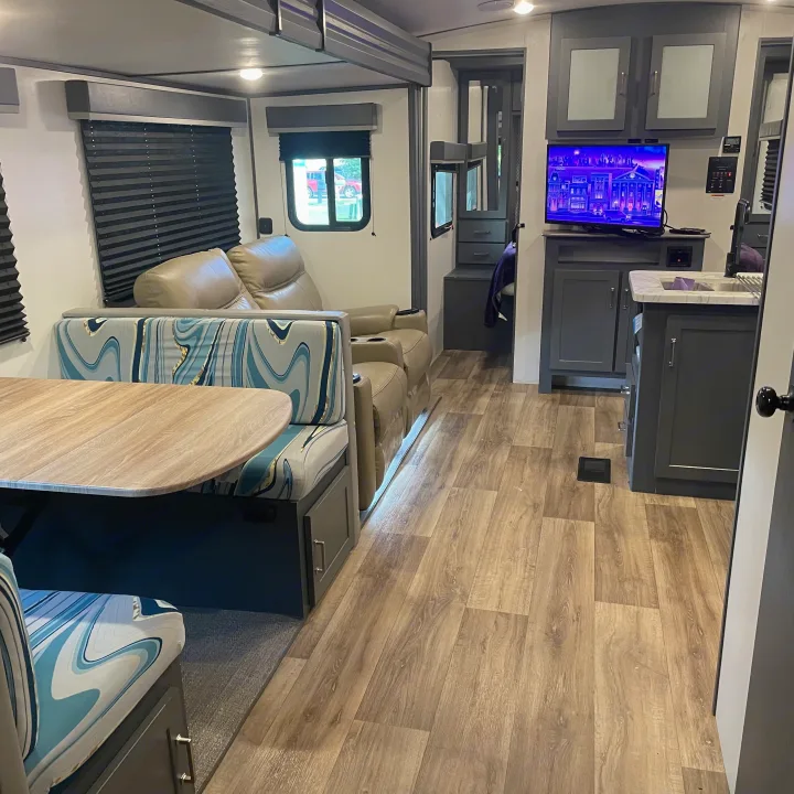 Modern RV rental interior: dining booth, recliners, kitchen, and wood floors. Comfortable and well-equipped.. Keystone RV Bullet Ultra Lite 2022