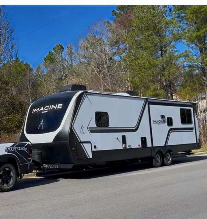 Imagine RV travel trailer hitched to a Ram Rebel truck, parked roadside. An ideal rv rental for outdoor adventures.. Grand Design Imagine 3100RD 2025