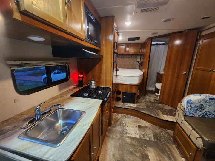 Inside a bright RV rental: full kitchen with sink/stove, comfortable bedroom, and compact bathroom for your travels.. Coachmen Leprechaun 220QB 2019