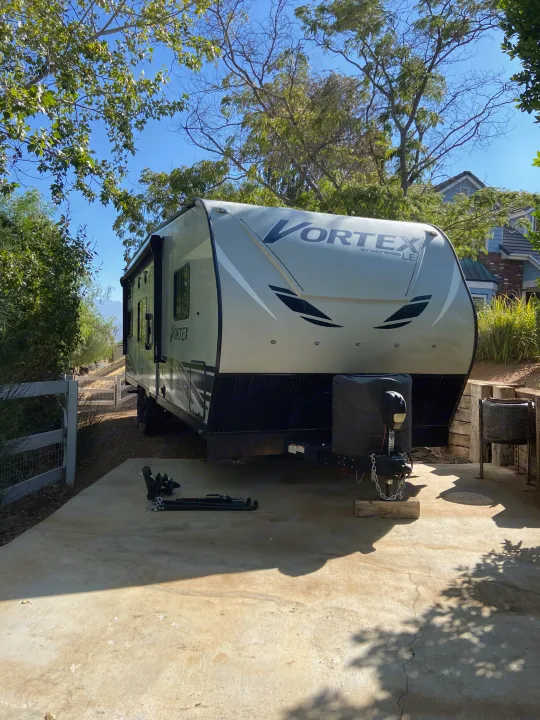 A Vortex by Genesis LE travel trailer is parked on a concrete slab outdoors. Consider this RV rental for your next adventure!. Genesis Supreme Rv Genesis Supreme 2022