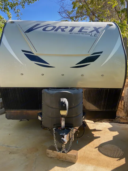 Front view of a Vortex travel trailer, ready for your next RV rental trip. Shows propane tank cover & hitch.. Genesis Supreme Rv Genesis Supreme 2022
