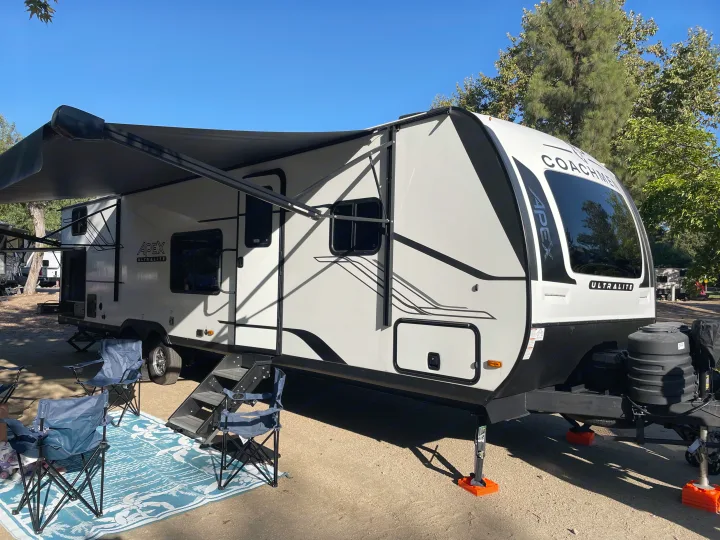 Spacious RV rental set up at a sunny campsite with an extended awning and chairs, perfect for travel and camping adventures.. Coachmen Apex 300 BHS 2025