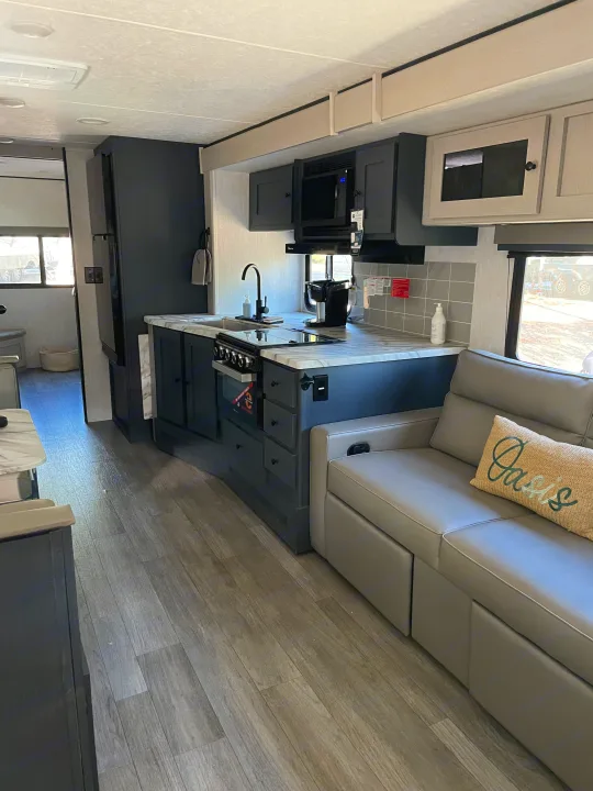Modern RV rental interior with a sleek grey kitchen, comfortable sofa, and wood-look flooring.. Coachmen Apex 300 BHS 2025