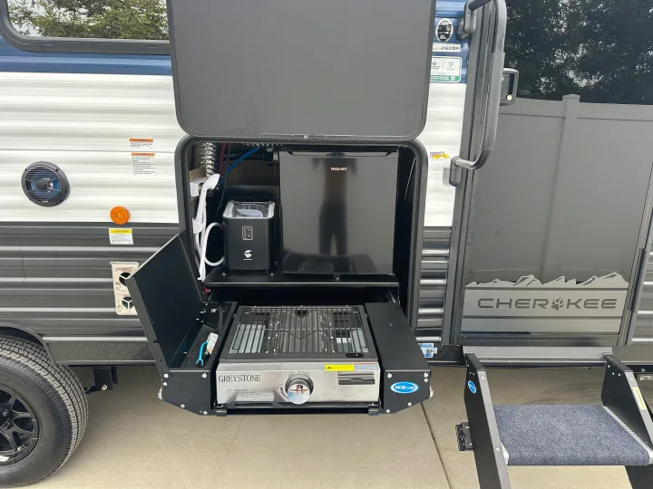 Explore this RV rental's outdoor kitchen featuring a Hotpoint mini-fridge, ice maker, and Greystone grill for your next adventure.. Forest River Cherokee Grey Wolf 2026