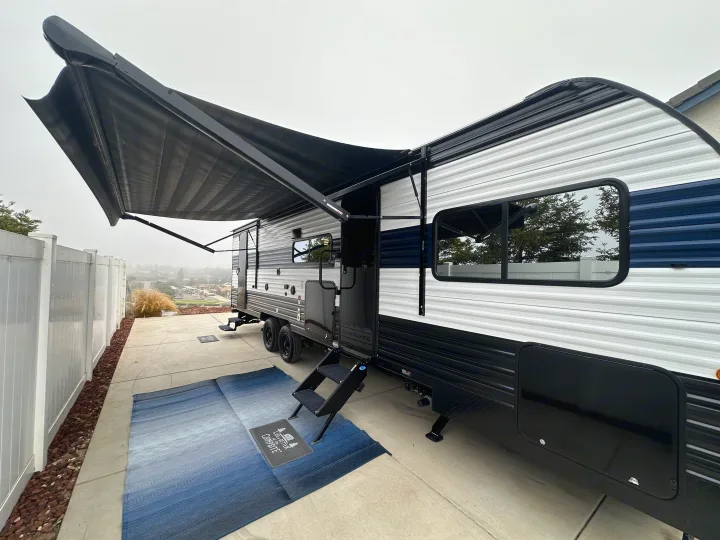 An inviting rv rental campsite setup with extended awning, steps, and an outdoor rug.. Forest River Cherokee Grey Wolf 2026