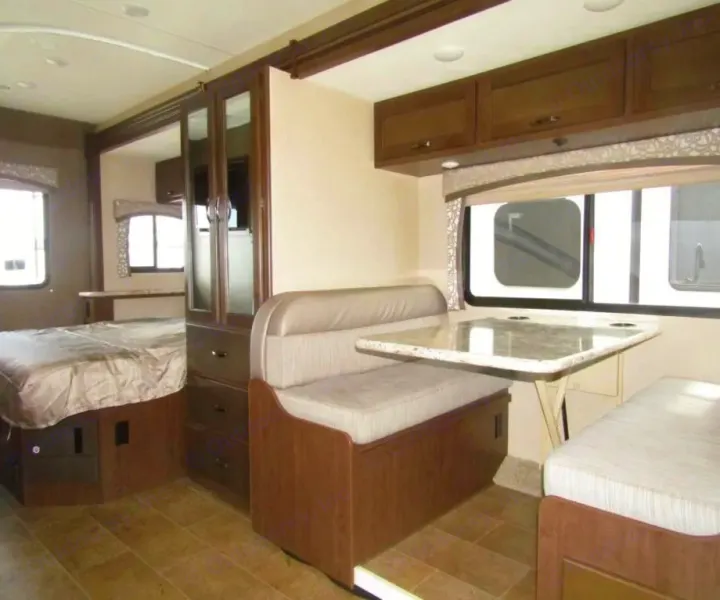 RV rental interior showcasing a comfortable bedroom, central wardrobe, and a bright dinette with table.. Thor Chateau 2019