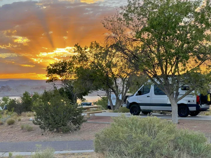 Stunning sunset with crepuscular rays over a lake and mountains, featuring an rv rental at a desert campsite.. Entegra Coach Launch 2023
