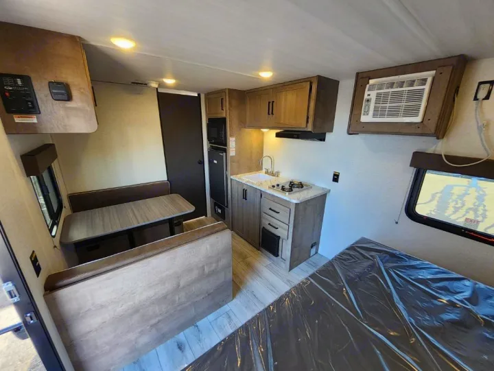 RV rental interior features a compact kitchen, dinette, and bed. Efficient design for comfortable travel and adventures.. Keystone Springdale Classic Mini 2025