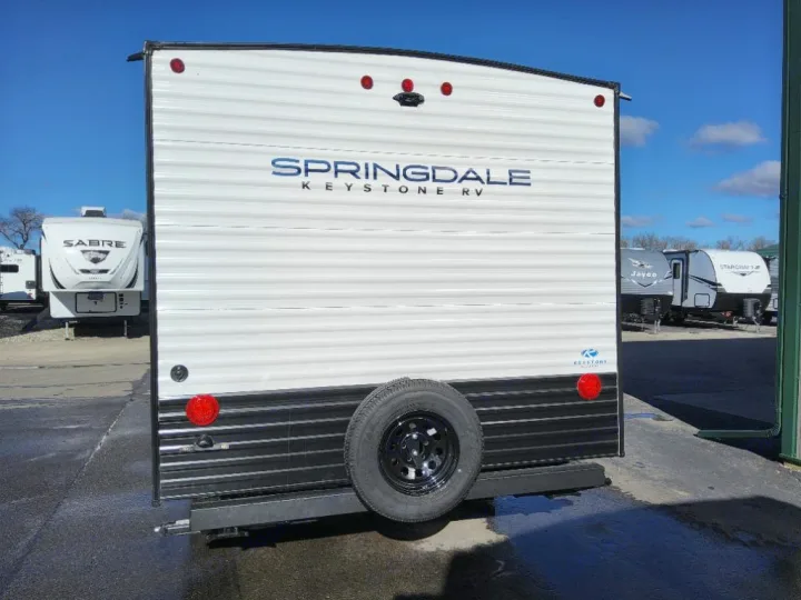 Explore the outdoors! Rear view of a white Springdale Keystone RV travel trailer with a spare tire, perfect for an rv rental.. Keystone Springdale Classic Mini 2025