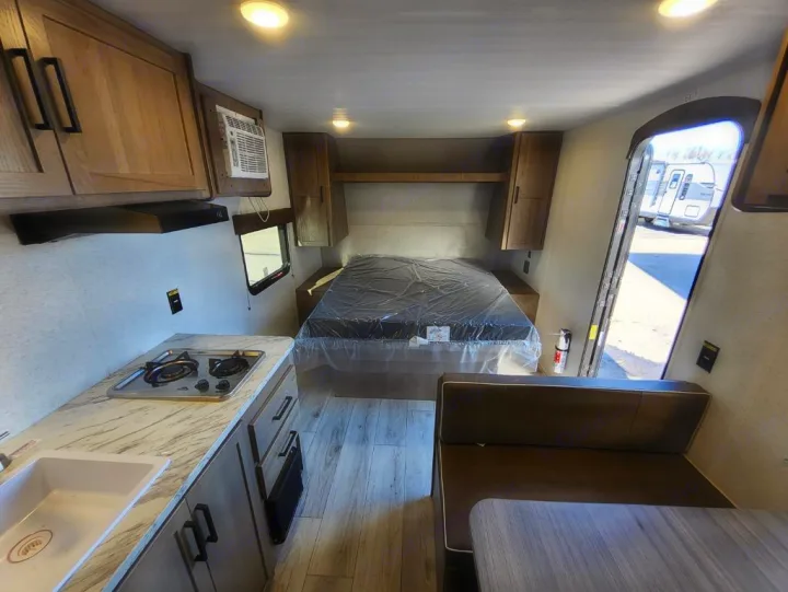 Inside your next rv rental! This camper features a kitchen with stove & sink, a cozy bed, and a dinette for eating and relaxing.. Keystone Springdale Classic Mini 2025