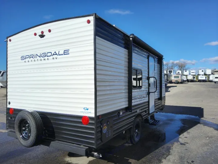 A white and black Springdale Keystone travel trailer RV, ideal for rv rental, parked on an outdoor lot.. Keystone Springdale Classic Mini 2025