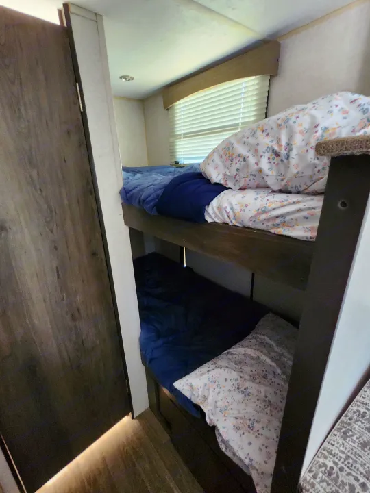 Cozy RV rental bunk beds featuring floral pillows, blue bedding, and window blinds for comfortable rest.. Forest River Viking 2020
