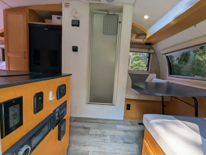 Interior of an RV rental, featuring a compact kitchen, central shower, and dinette. Designed for efficient travel and comfort.. Xtreme Outdoors Little Guy Max 2021
