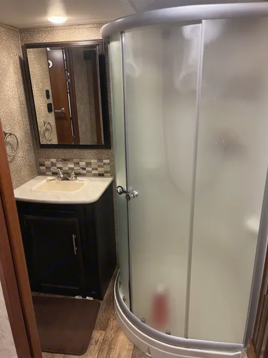 This RV rental features a compact bathroom with a sink vanity, mirror, and rounded frosted shower for comfortable travel.. Jayco Eagle HT 2017