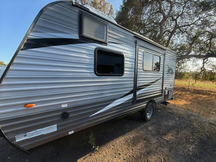 Side view of a grey Jayflight SLX travel trailer RV rental, featuring stripe design and tinted windows.. Jayco Jay Flight SLX 2021