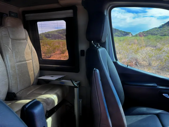 RV rental interior featuring swivel seats, a Lagun table, and a scenic window view of a desert mountain landscape.. Entegra Coach Launch 2023