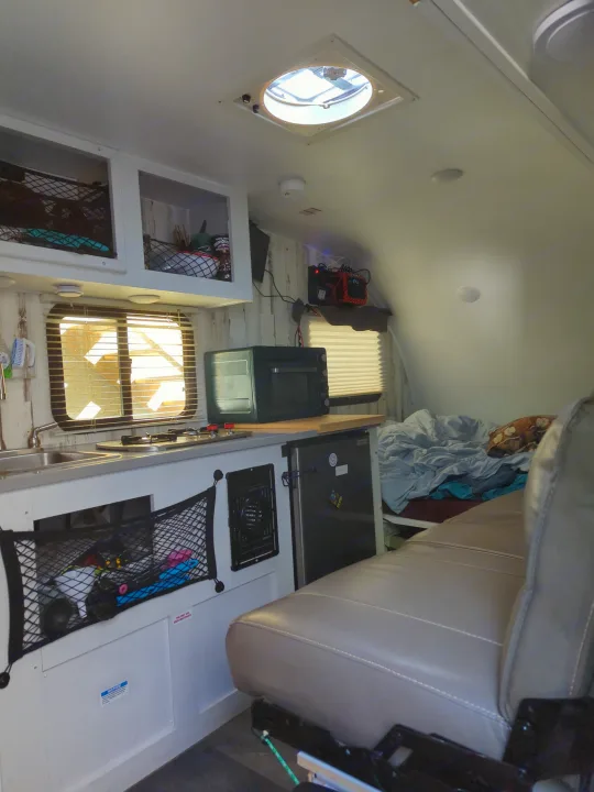 Step inside this RV rental! Compact kitchen with stove, sink, oven, and fridge, plus a comfortable bed area and seating. Efficient interior.. Travel Lite Rove Lite 2023