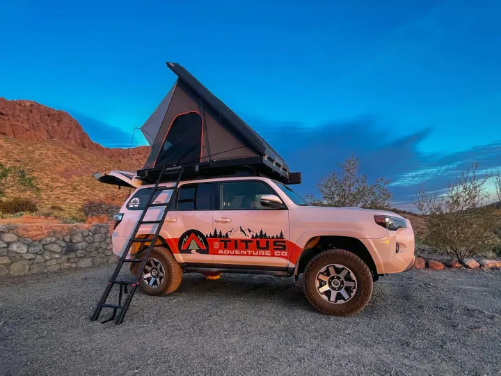 An adventure-ready SUV with rooftop tent & ladder, branded 'Titus Adventure Co.', great for outdoor rv rental.. Toyota 4Runner 2024