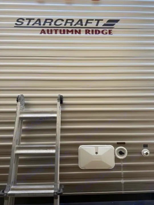 Light-toned Starcraft Autumn Ridge travel trailer with ladder and utility access ports, ideal for rv rental.. StarCraft Autumn Ridge 2013