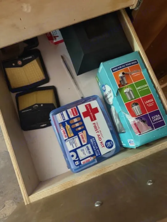 An RV rental's organized drawer: First Aid Kit, trash bags, and portable Cucuner solar lights, ready for adventures.. StarCraft Autumn Ridge 2013