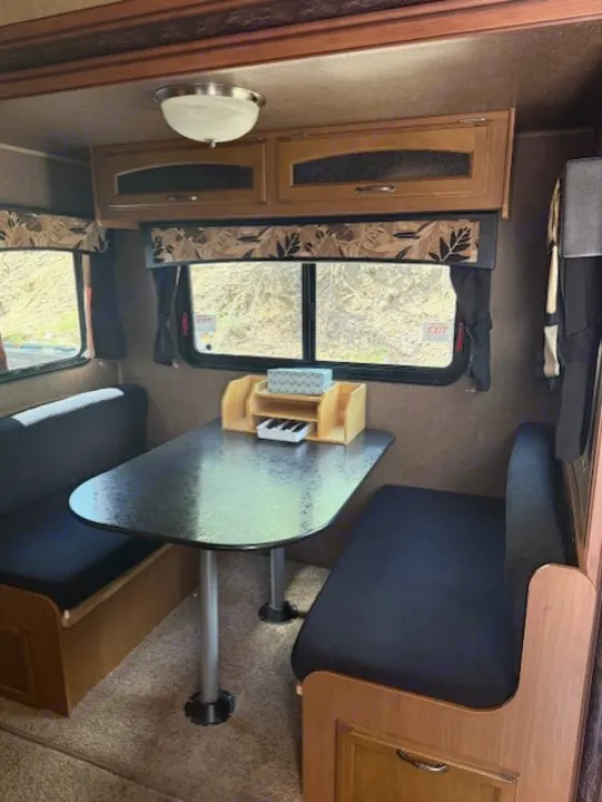 RV rental interior: A cozy dinette with a black table, benches, overhead cabinets, and windows offering natural light.. StarCraft Autumn Ridge 2013