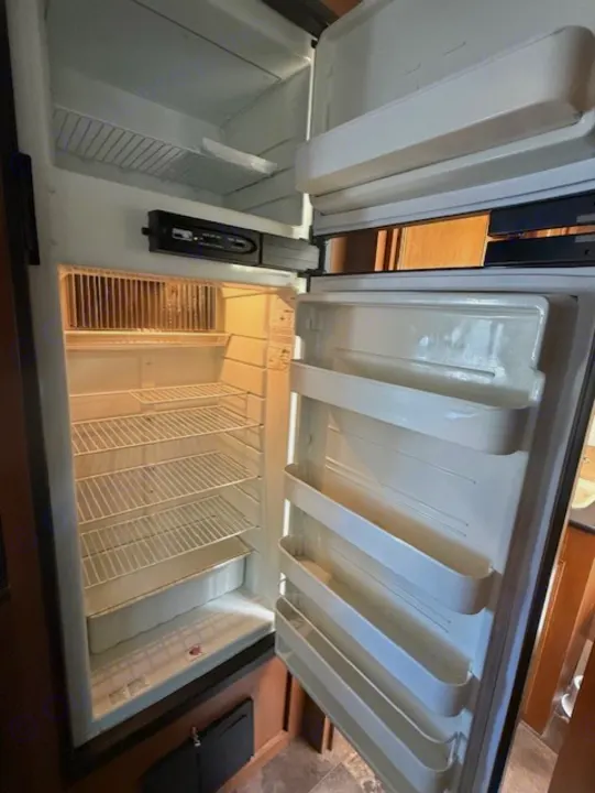 Clean, empty RV rental refrigerator, featuring wire shelves & door storage, ready for your next adventure.. StarCraft Autumn Ridge 2013