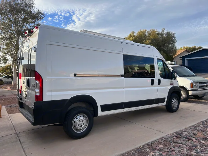 White Ram ProMaster camper van, often used for RV rental, showcasing its rear ladder and roof solar panels.. Ram Promaster 2500 2022