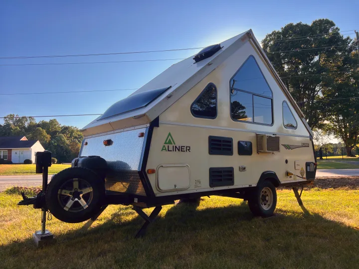 An A-Liner Expedition A-frame RV rental, ready for your next adventure, parked on green grass under a clear sky.. A Liner A Liner Popup Trailer 2013