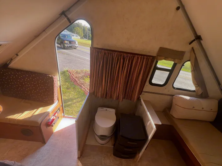 Compact RV rental interior, featuring bench seating, portable toilet, and storage for comfortable travel.. A Liner A Liner Popup Trailer 2013