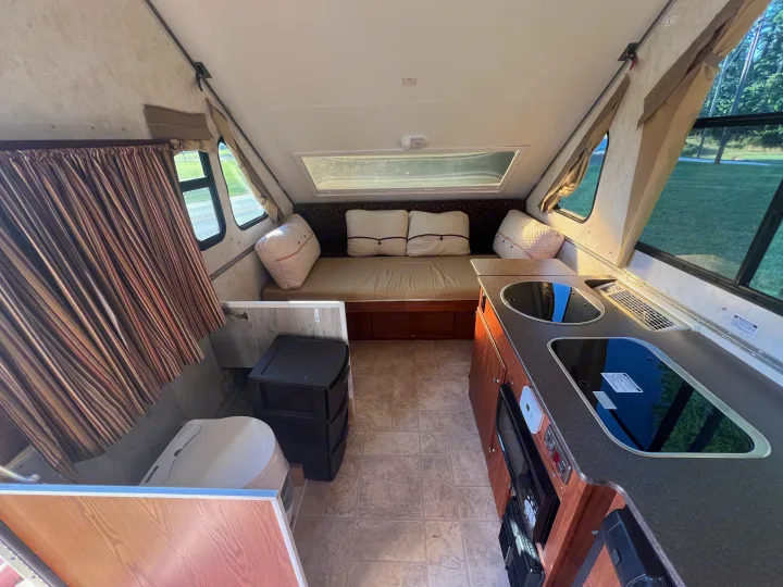 This clean RV rental offers a compact kitchen, comfortable sleeping area, and portable toilet, ideal for travel.. A Liner A Liner Popup Trailer 2013