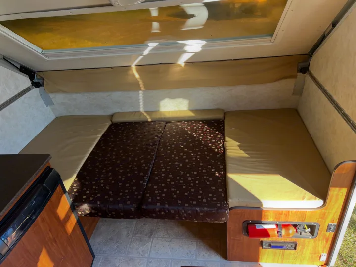 RV rental interior: light-filled space with cushioned seating, a small kitchen, and safety features like a fire extinguisher.. A Liner A Liner Popup Trailer 2013