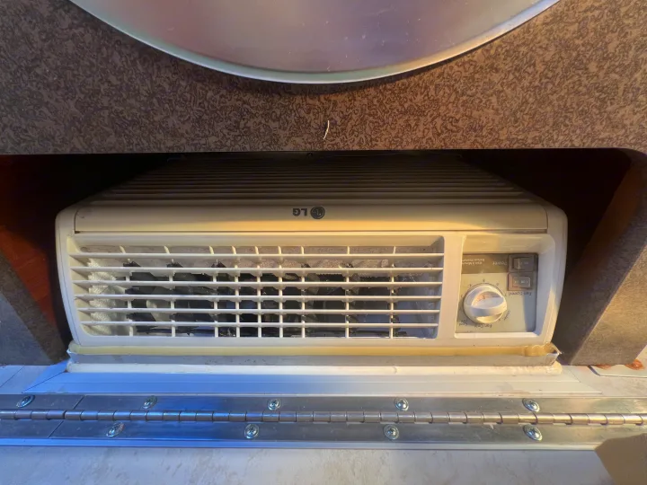 Dusty LG air conditioner unit with controls and vents, common in an RV rental interior.. A Liner A Liner Popup Trailer 2013