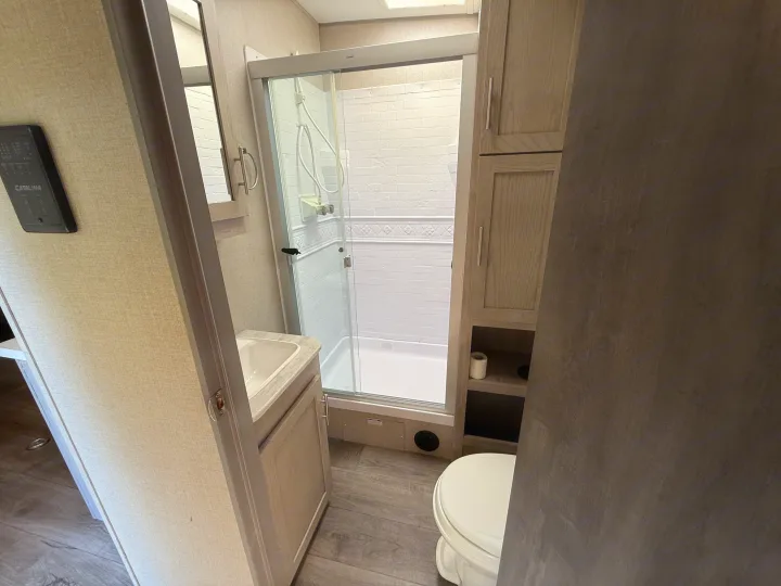 RV rental bathroom features a compact layout with a glass-enclosed shower, vanity, and toilet.. Coachmen Catalina 2022