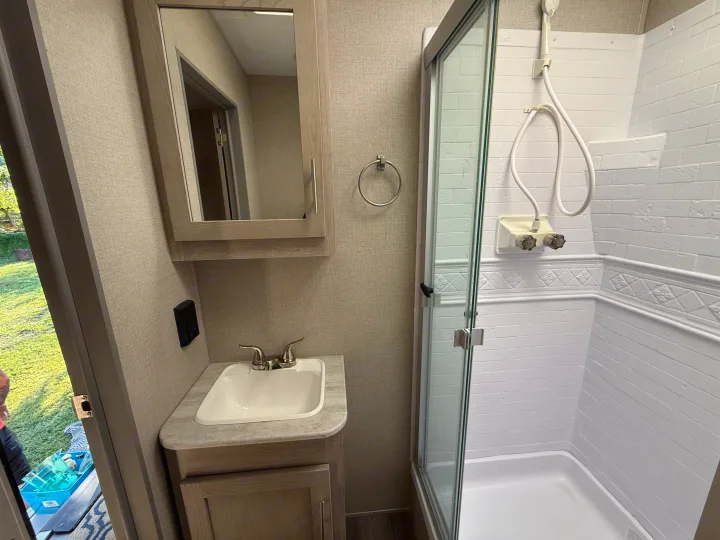 RV rental bathroom featuring a sink, medicine cabinet, shower with glass door, and towel ring.. Coachmen Catalina 2022