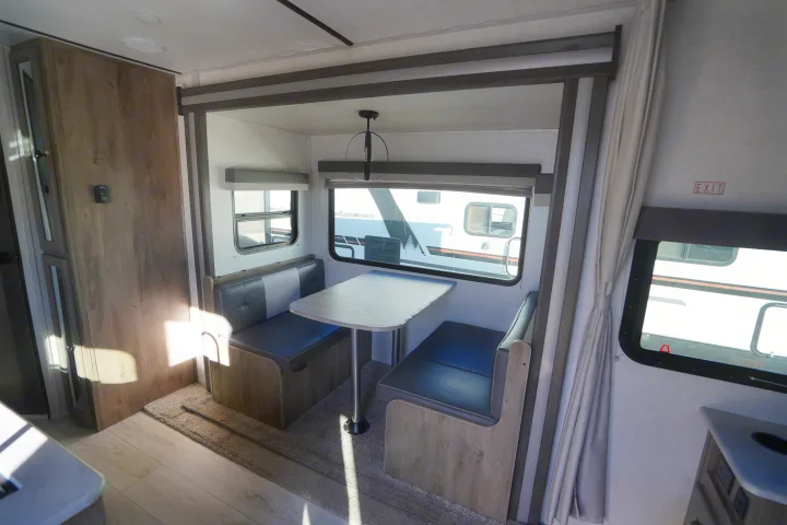 Cozy rv rental dinette with seating, table, windows, and bright interior light, perfect for meals on the road.. Forest River Surveyor Legend 2022