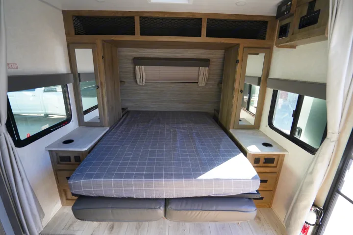 Spacious RV rental bedroom featuring a comfortable bed, dual nightstands with power, and overhead storage for comfortable travel.. Forest River Surveyor Legend 2022