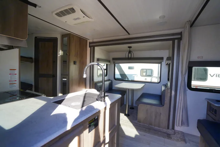 Bright RV rental interior showcasing a well-equipped kitchen, versatile dinette, and sleeping bunk beds.. Forest River Surveyor Legend 2022
