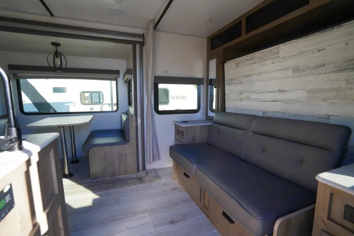 Modern RV rental interior: gray sofa, light wood dinette, bright walls. Enjoy comfortable travel.. Forest River Surveyor Legend 2022