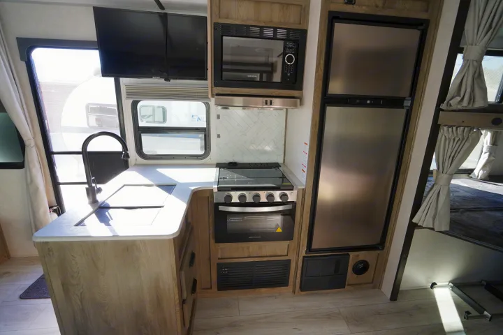 Modern RV rental kitchen featuring a compact layout with sink, stove, microwave, and refrigerator for easy living.. Forest River Surveyor Legend 2022